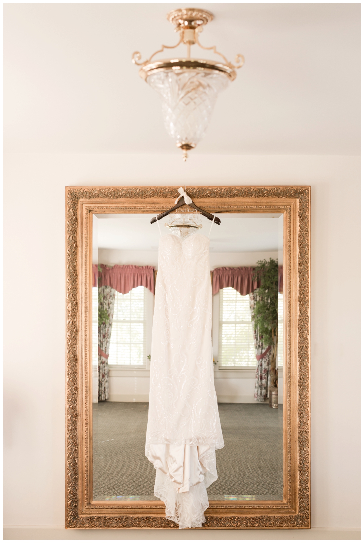 Bride's wedding dress hanging on a mirror with lace details