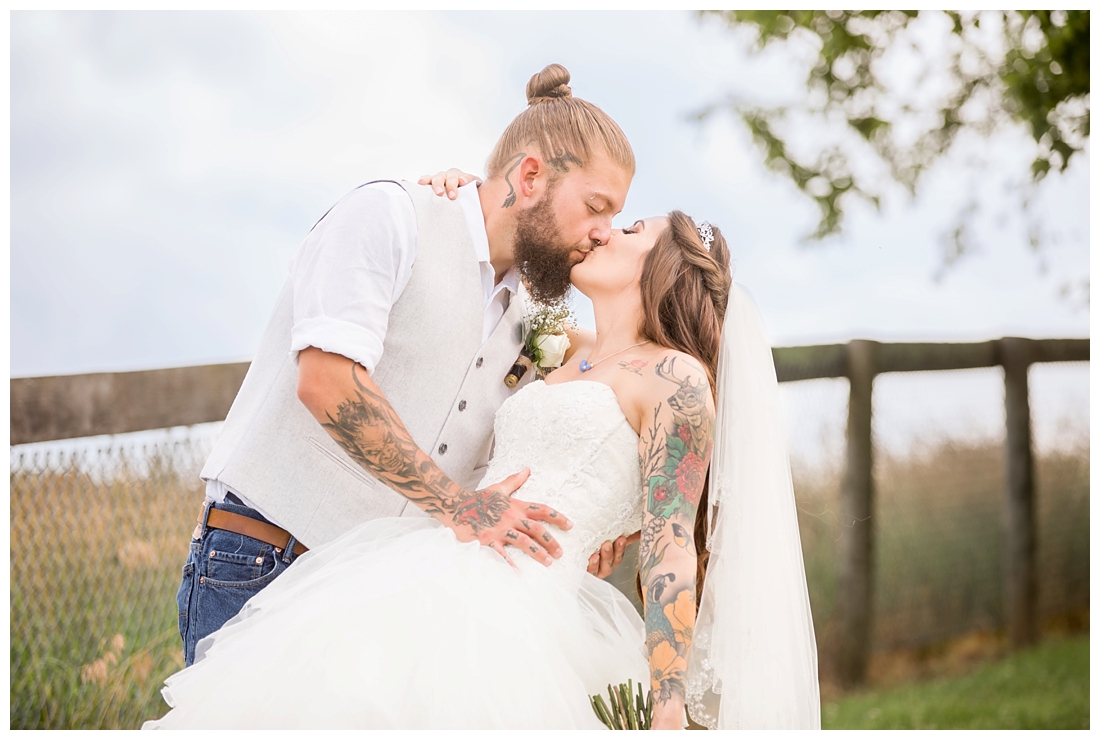 Outdoor bride and groom portraits. Bride and groom against a fence and a field. Maryland wedding at Circle D Farm in Woodbine. Maryland Wedding Photographer.